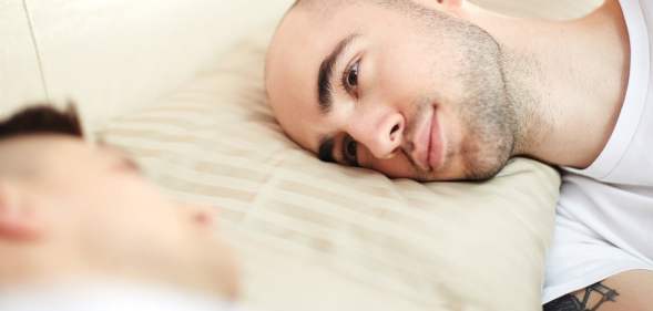 Young man with his head on pillow lying in bed and looking at his lover