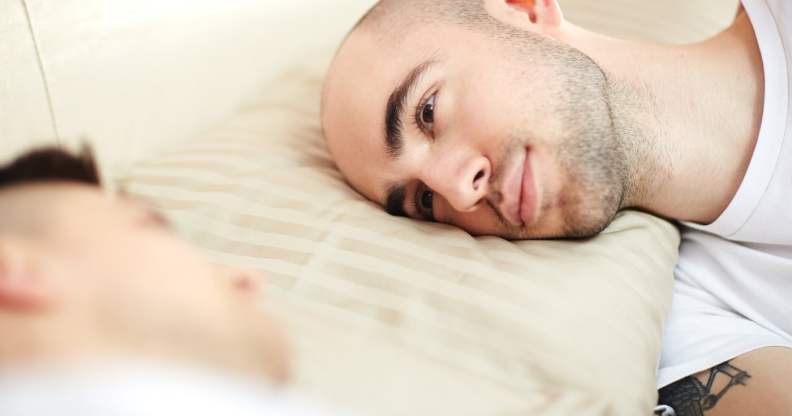 Young man with his head on pillow lying in bed and looking at his lover