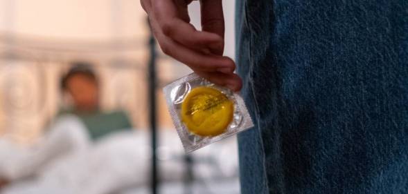 Person holds a condom behind their back while staring at their partner. This image is used to illustrate California lawmakers have sent a bill banning secretly removing a condom during sex – commongly known as 'stealthing' – to governor Gavin Newsom.