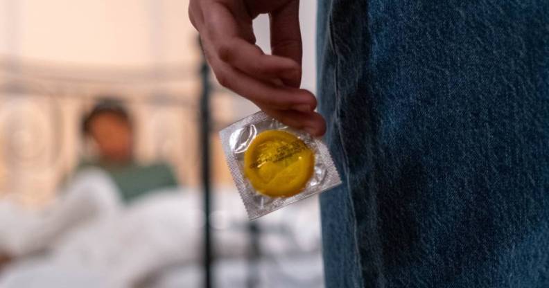 Person holds a condom behind their back while staring at their partner. This image is used to illustrate California lawmakers have sent a bill banning secretly removing a condom during sex – commongly known as 'stealthing' – to governor Gavin Newsom.