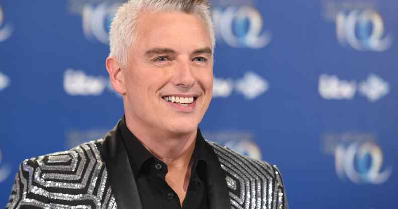 John Barrowman in a glitzy silver and black suit, smiling