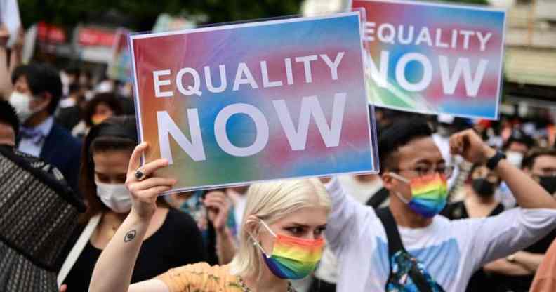 People hold up signs reading 'equality now' during a rally organised by an activist group in support of LGBT+ legislation in Shibuya district of Tokyo, Japan