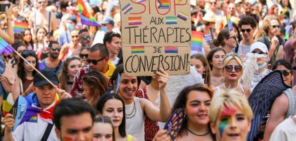 A Pride March participant holds up a sign written in French that calls for the end of conversion therapies