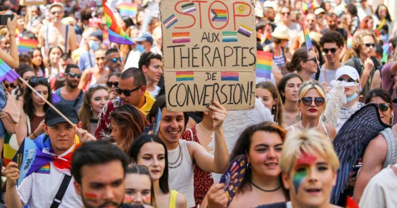 A Pride March participant holds up a sign written in French that calls for the end of conversion therapies