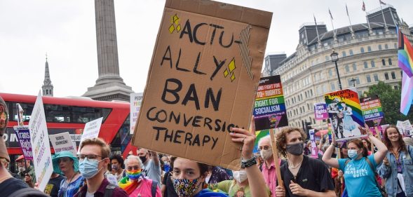 A protestor holds a conversion therapy ban placard