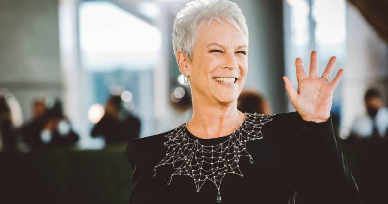 Jamie Lee Curtis waves at the crowds in a black dress with a collar designed to look like spider web