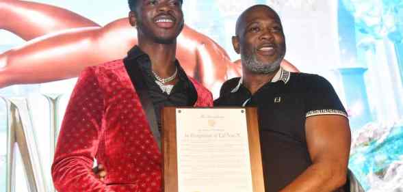 A picture of Lil Nas X and his father Robert Stafford holding up a plaque at a homecoming event for the rapper in Atlanta Georgia