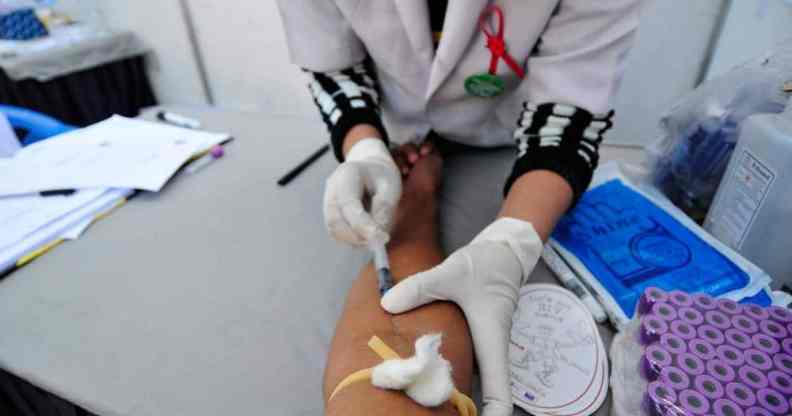 A medical official takes blood from a person for rapid HIV testing