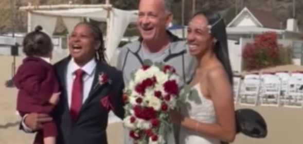 Tom Hanks posing inbetween a couple at their wedding