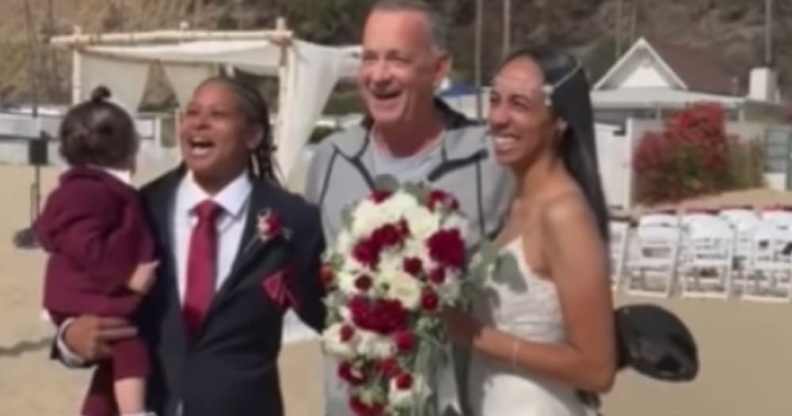 Tom Hanks posing inbetween a couple at their wedding