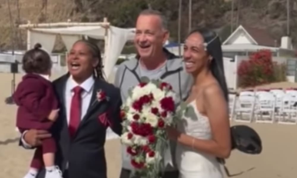 Tom Hanks posing inbetween a couple at their wedding