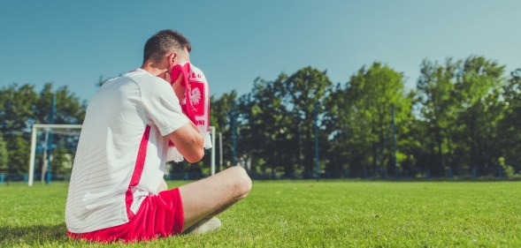 Man sitting on a football pitch crying