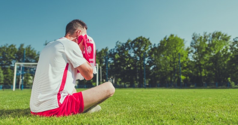 Man sitting on a football pitch crying