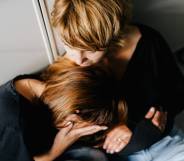 two people are holding each other as one person appears to be crying