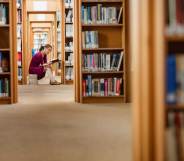 Young woman reading book in library at college