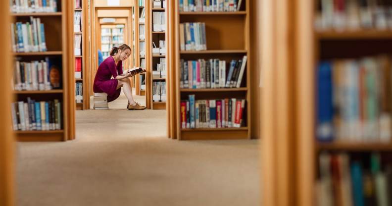 Young woman reading book in library at college