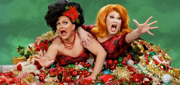 Jinkx Monsoon and BenDeLaCreme bursting out of a pile of presents.