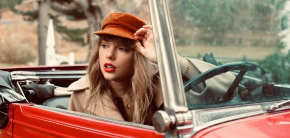 Taylor Swift sitting in a car in a promotional image for Red (Taylor's Version)