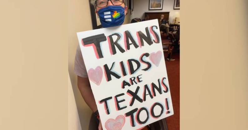 Hillary Moore-Embry holds up a sign that reads "Trans Kids are Texans Too!" in support of the trans community in Texas