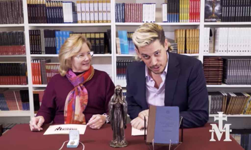 Milo Yiannopolous and a woman sat at a desk with a Virgin mary statue