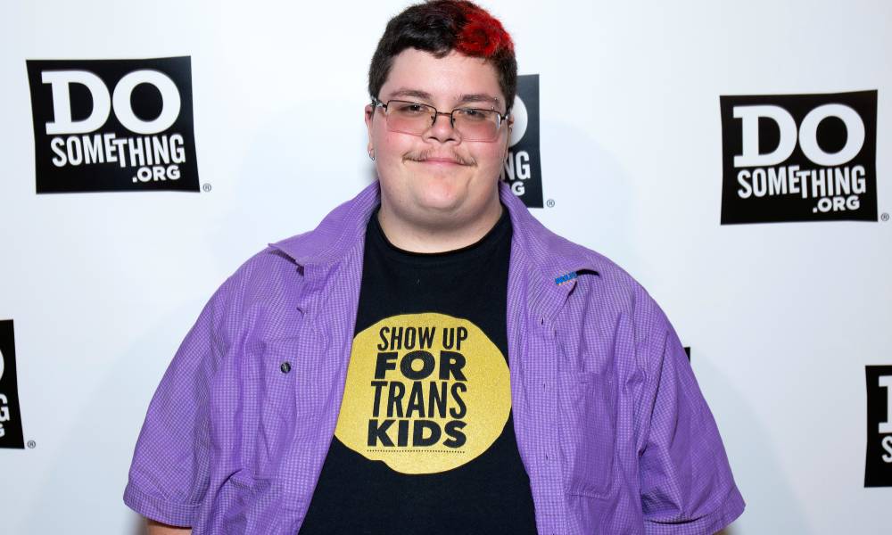 Gavin Grimm attends the 2019 DoSomething Gala in a black shirt with the words 'show up for trans kids' and a purple button up shirt