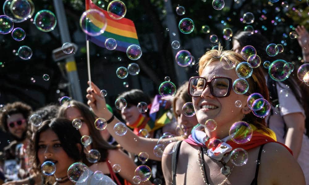 Members of the LGBT+ community in Switzerland celebrate Zurich Pride holding rainbow LGBT+ flags and walking through a wave of bubbles