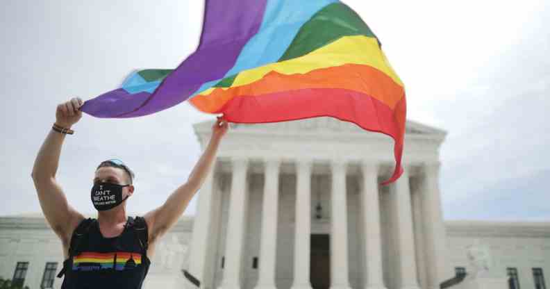 A person holds an LGBTQ+ Pride flag outside the US Supreme Court