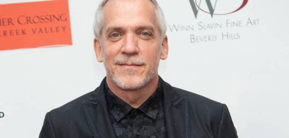Director Jean-Marc Vallée poses in a black shirt and suit jacket in front of a white background