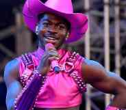 Lil Nas X performs in a hot pink outfit and matching cowboy hat holding a hot pink microphone