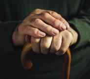 Fingers of an old man clasping a walking stick