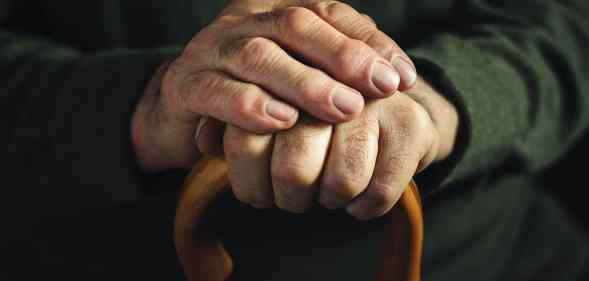 Fingers of an old man clasping a walking stick