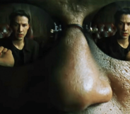 Morpheus wearing reflective sunglasses. In them, you can see Neo reaching for the Red Pill