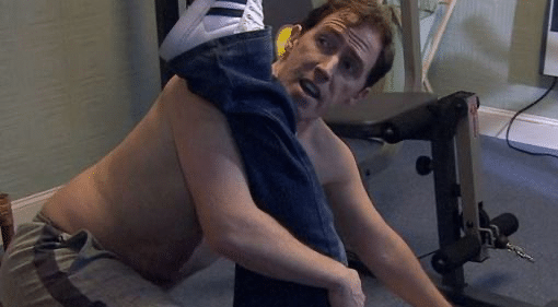 Rob Brydon as Bryn, topless. with a man's leg over his shoulder