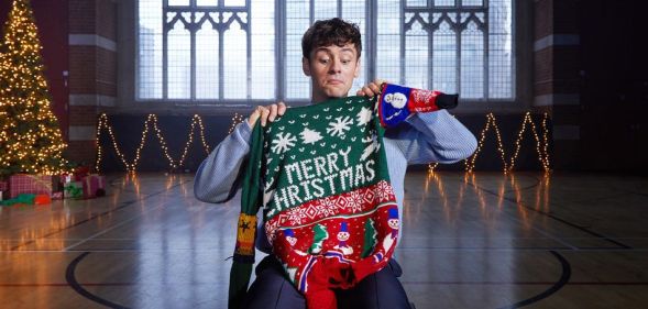 Tom Daley holding up a Merry Christmas jumper