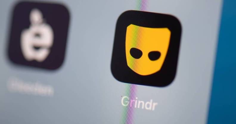 the black and yellow Grindr logo can be seen on the screen of a phone