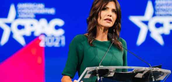 South Dakota governor Kristi Noem speaks at a podium while dressed in a green outfit