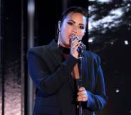 Demi Lovato is dressed in all black as they sing into a microphone