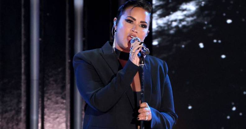 Demi Lovato is dressed in all black as they sing into a microphone
