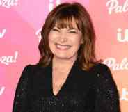 Lorraine Kelly smiles at the camera while wearing a black sparkly outfit