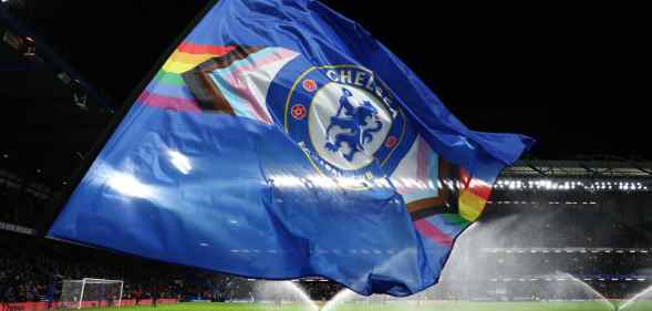 A flag bearer waves a Chelsea FC flag with the LGBT+ Progress flag design