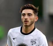 Joshua Cavallo wears a white and black patterned football jersey as he warms up before a match