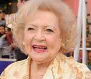 Betty White smiles at the camera while wearing a light yellow patterned top
