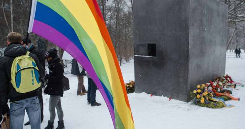 A man holds a rainbow flag during an event to commemorate the homosexual men and women who were persecuted by the Nazis dunring the Holocaust on January 27, 2014 in Berlin, Germany.