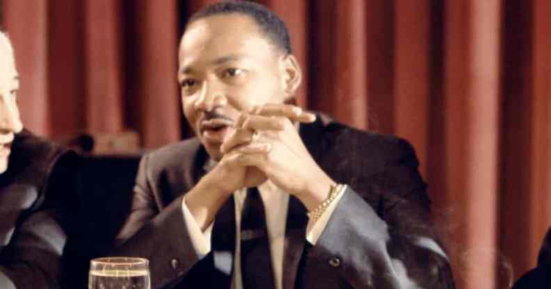 Martin Luther King Jr sits at a table with his hands folded in front of his face