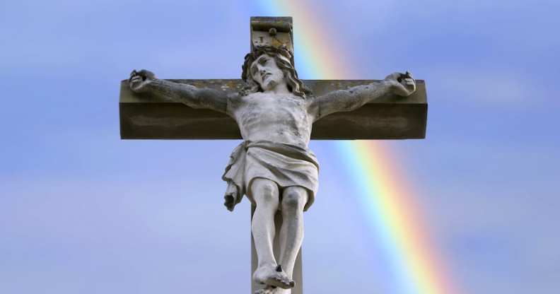 statue of Jesus on a crucifix in front of a rainbow