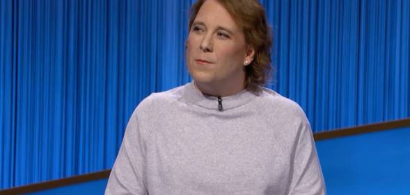 Amy Schneider appears on the set of Jeopardy! in a grey or cream top