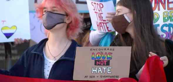 People hold a sign that reads 'Encourage love not hate at SDA + everywhere'