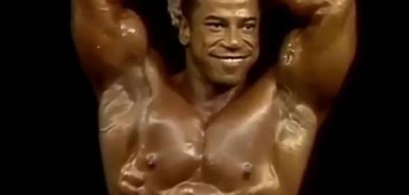 Chris Dickerson smiles and poses while flexing his muscles in a bodybuilding competition