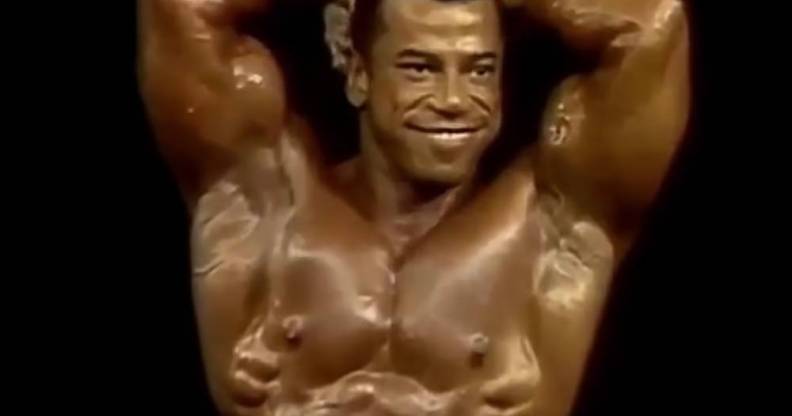 Chris Dickerson smiles and poses while flexing his muscles in a bodybuilding competition