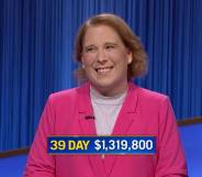 Jeopardy! champion Amy Schneider wears a pink top and darker pink jacket as she smiles after she wins her 39th consecutive game